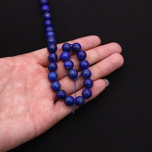 Macro detail of natural blue lapis lazuli beads with golden pyrite flecks held in hand