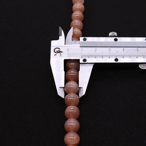Macro detail of 8mm natural sunstone beads being measured with a precision caliper