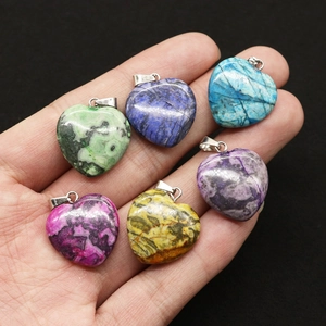 Set di ciondoli in pietra naturale a forma di cuore in vari colori nella mano