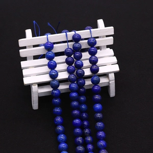 Polished dark blue lapis lazuli beads with natural golden pyrite specks on wooden stand