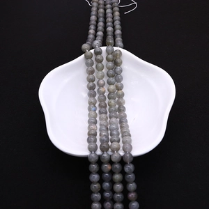 Macro detail of natural labradorite grey beads on a white ceramic flower tray