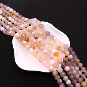 Macro detail of natural cherry blossom agate beads with floral textures on a white tray