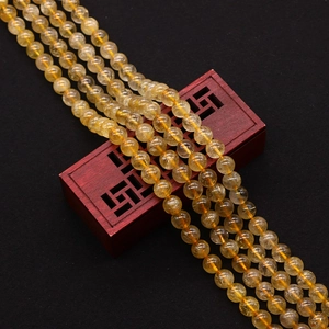 Macro detail of golden rutilated quartz beads with needle inclusions in a wooden box
