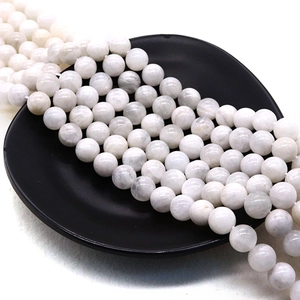 Translucent white moonstone round beads arranged in a black tray for jewelry DIY