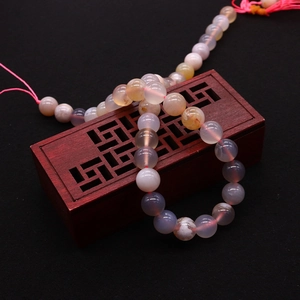 Polished natural agate beads with pink tassel on vintage wooden jewelry box
