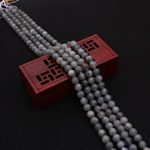 Macro detail of natural labradorite beads with blue flash on a red vintage wooden box