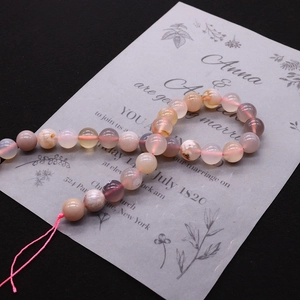 Macro detail of mixed pink and orange cherry agate round beads on a vintage card background
