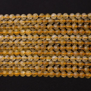Polished natural yellow crystal round beads on orange cord against a black background