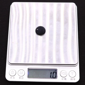 Pendentif rond plat en coquille noire sur balance numérique pesant 1,0 gramme pour bijoux