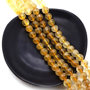 Polished natural yellow crystal round beads on black matte tray for jewelry making