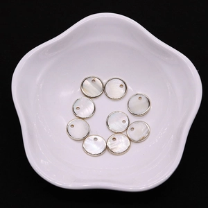 Vue macro de pendentifs ronds en nacre naturelle de 15 mm avec bord doré sur plat blanc