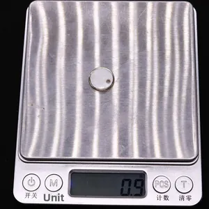 Balance numérique affichant le poids de 0,9 gramme d'un pendentif en nacre de 15 mm