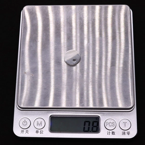 Détail d'un pendentif rond en nacre de 15mm sur une balance pesant 0,8g pour bijoux DIY