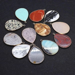 Detailed view of teardrop natural stone pendants with gold-plated metal edges for jewelry DIY