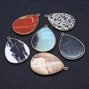 Macro detail of teardrop natural stone pendants with gold plating and various patterns