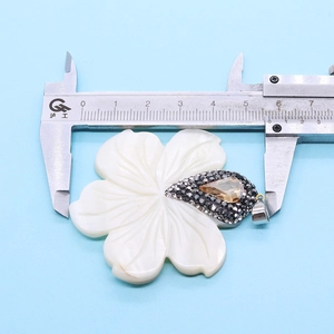 Meten van een 57mm natuurlijke schelp bloem hanger met een schuifmaat op blauw