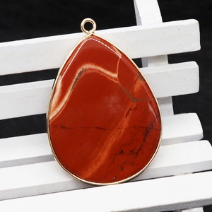 Natural red jasper teardrop pendant with gold metal border on white chair display