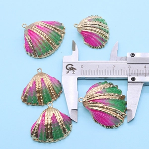 Détail de cinq pendentifs en forme de coquille avec bordure dorée et mesure de 25 mm