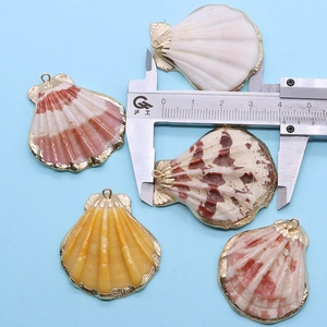 Détail de pendentifs en coquillage naturel coloré mesurés avec un pied à coulisse