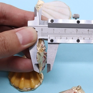 Mesure de l'épaisseur de 8mm d'un pendentif coquillage doré à l'aide d'un pied à coulisse