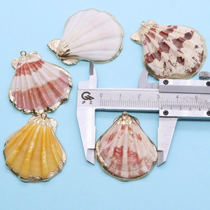 Vue détaillée de pendentifs coquilles saint-jacques dorés avec mesure au pied à coulisse