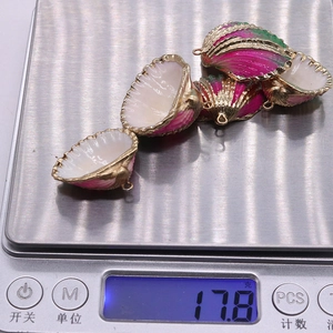 Détail de quatre pendentifs en coquillage colorés avec bordure dorée sur une balance précise