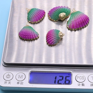 Détail de cinq pendentifs coquillages violets sur une balance affichant un poids de 12,6g