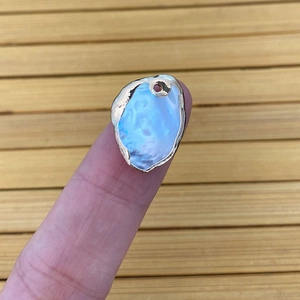 Pendentif en perle d'eau douce naturelle irrégulière avec bordure dorée sur le doigt