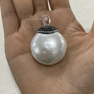 Hand holding large 32mm round white shell pendant with micro-paved crystal inlay