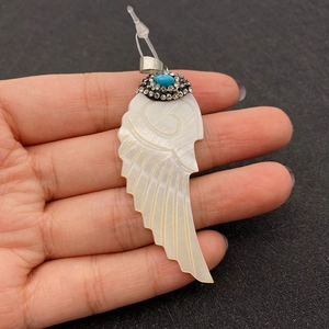 Detailed macro of white shell wing pendant with blue stone and sparkling rhinestones