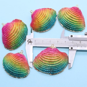 Detailed view of rainbow scallop shell pendants with gold edges and measuring caliper