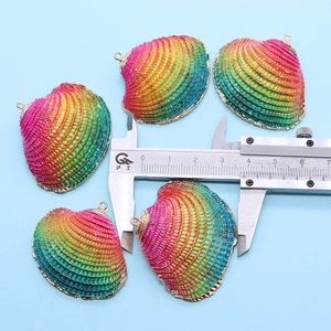 Macro shot of colorful gradient shell pendants with gold edges measured by a caliper