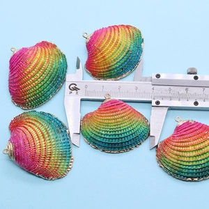 Macro shot measuring colorful shell pendant with gold trim using a caliper tool