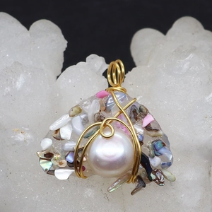 Macro detail of handmade resin pearl pendant with gold wire wrapping and shell flakes