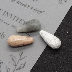 Macro shot of faceted teardrop gemstone beads in grey, moonstone pink, and white turquoise