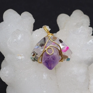 Macro detail of handmade wire wrapped amethyst pendant with clear resin and gold wire
