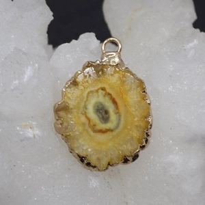 Macro detail of yellow sunstone pendant with gold plated rim on white crystal stone
