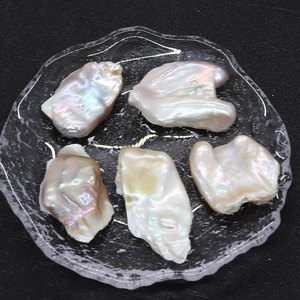 Primer plano de perlas barrocas naturales con fuerte brillo arcoíris en plato cristal