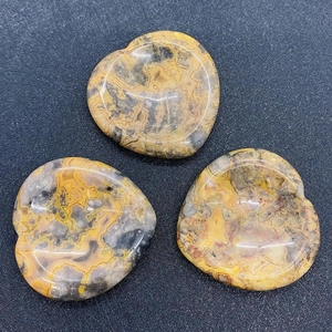 Gros plan de trois pierres de jaspe en forme de cœur polies sur un fond de maille sombre