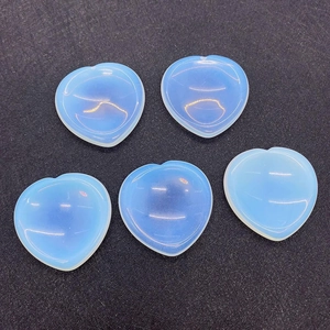 Flat lay of five polished heart-shaped opal worry stones on a black textured background