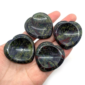 Polished heart-shaped dragon blood stone massage stones held in hand for scale