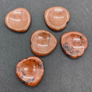 Macro shot of polished mahogany obsidian heart-shaped thumb stones for crystal healing