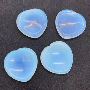 Macro shot of four heart-shaped opalite worry stones arranged on a textured black surface