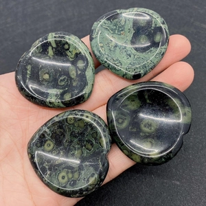Close-up of heart-shaped green Kambaba Jasper worry stones held in a person's hand