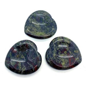 Macro detail of three heart-shaped bloodstone massage stones with polished concave surface