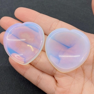 Close-up of heart-shaped opal thumb stones with blue sheen held in a hand