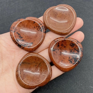 Macro view of four polished heart-shaped mahogany obsidian worry stones held in a palm