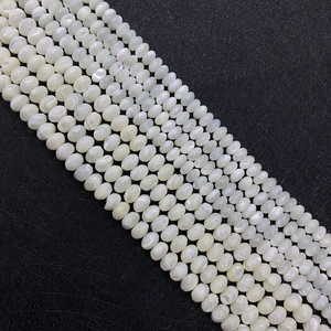 Perles de nacre blanches polies pour bijoux DIY soigneusement disposées sur un fond sombre