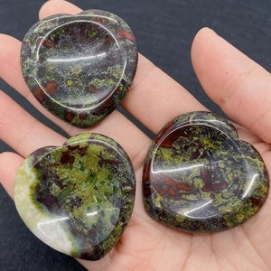 Macro shot of three heart-shaped dragon blood stones with concave thumb massage design