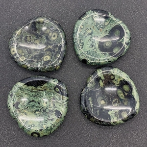 Detailed close-up of polished Kambaba Jasper heart-shaped thumb stones with orbicular patterns